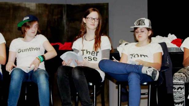 Fünf Jugendliche sitzen auf Stühlen und halten Skripte in der Hand.