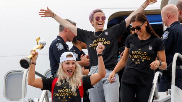 U.S. soccer players Julie Ertz, Rapinoe and Morgan celebrate as they exit the plane with the Trophy for the FIFA Women's World Cup while the U.S team arrive at the Newark International Airport, in Newark, New Jersey