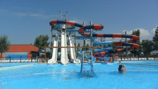 Ein Wasserpark mit mehreren Rutschen und einem Schwimmbecken an einem sonnigen Tag.