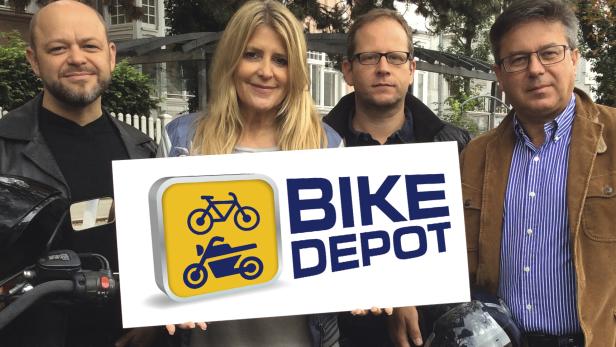 Vier Personen halten ein Schild mit der Aufschrift „Bike Depot“.