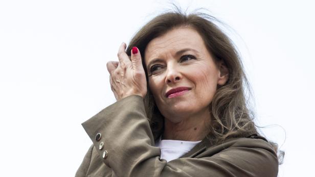 Eine Frau mit braunen Haaren und einem braunen Blazer blickt nach oben.