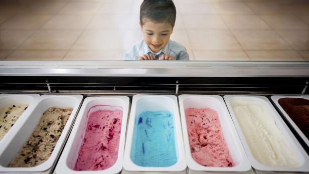 Kind überlegt, welches Eis es möchte.