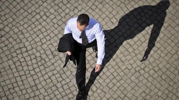 Ein Mann in Anzug und Krawatte geht über einen gepflasterten Platz.