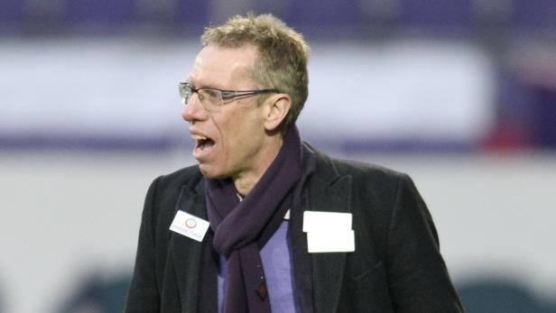 Ein Mann mit Brille und Schal gestikuliert auf dem Spielfeld.