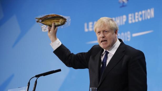 Boris Johnson mit einem plastikverpackten Fisch