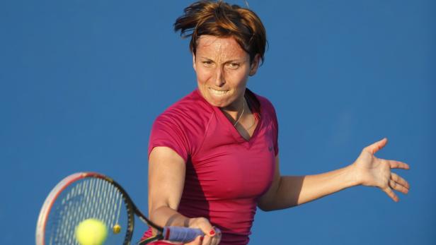Eine Tennisspielerin schlägt einen Ball mit ihrem Schläger.