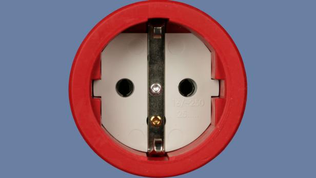 Eine rote Schutzkontakt-Steckdose vor blauem Hintergrund.