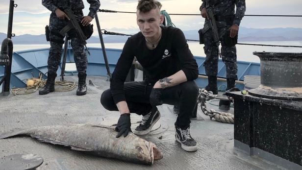 Jack Hutton von der Meeresschutz-Organisation Sea Shepherd untersucht einen toten Totoaba, während zwei mexikanische Navy-Offiziere Wache im Hintergrund stehen.