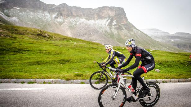 Zwei Radfahrer fahren eine Bergstraße entlang.