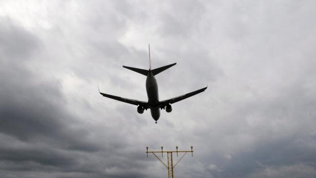 Ein Flugzeug landet vor einem bewölkten Himmel.