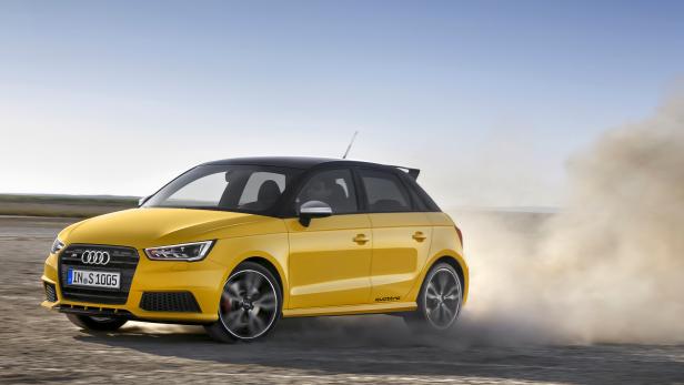 Ein gelber Audi S1 Quattro fährt auf einer staubigen Straße.