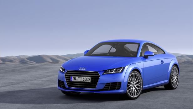 Ein blauer Audi TT steht vor einer Hügellandschaft.