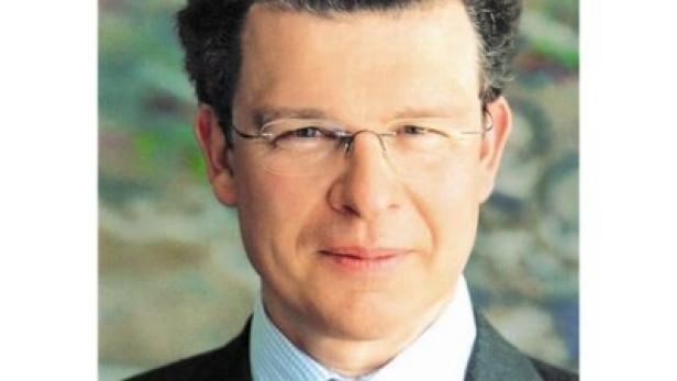 Ein Mann mit Brille, Anzug und roter Krawatte blickt in die Kamera.