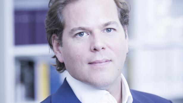 Ein Mann mit hellen Haaren und blauen Augen trägt ein blaues Jackett.