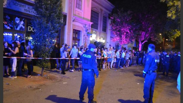 Polizisten sichern eine Menschenmenge vor einem Gebäude ab.