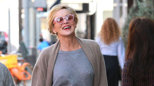 Sharon Stone lächelt mit rosafarbenen Sonnenbrille auf der Straße.