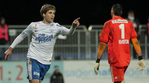 Ein Fußballspieler jubelt und zeigt auf den gegnerischen Torwart Novota.