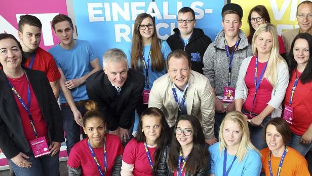 Eine Gruppe von Menschen posiert vor einem farbenfrohen Hintergrund mit der Aufschrift „Einfallsreich“.