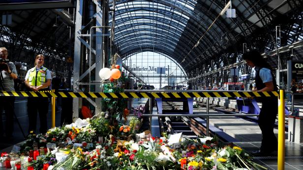 Messages of mourning, candles and flowers are placed by people for an eight-year-old boy who was pushed by a man in front of an oncoming train and died at the main train station in Frankfurt