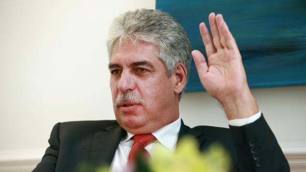 Ein Mann im Anzug hebt die Hand.
