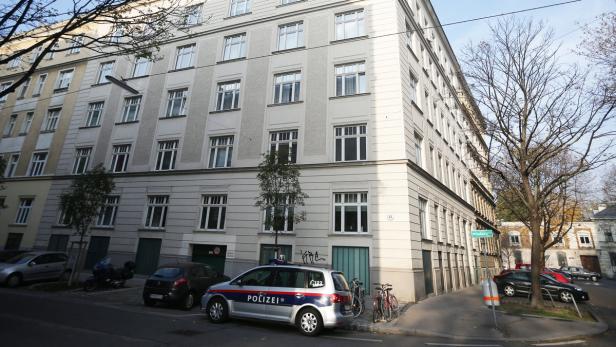Ein Polizeiauto parkt vor einem mehrstöckigen Gebäude in einer Stadt.