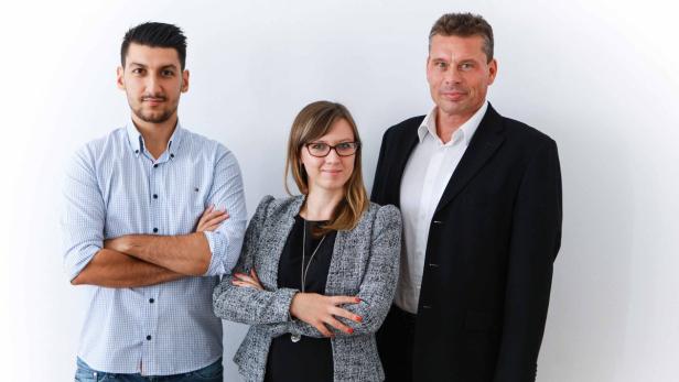 Drei Personen posieren vor einer weißen Wand.