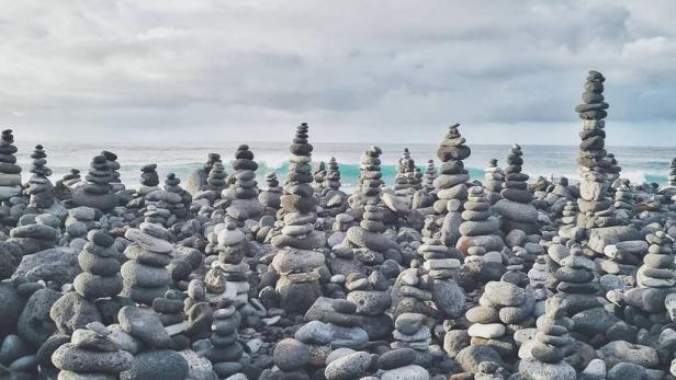 Am Strand sind viele Steintürme aufgeschichtet.