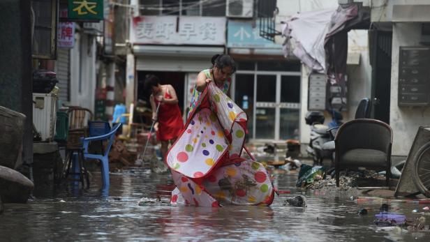 People clean a flooded street after typhoon Lekima hit Linhai