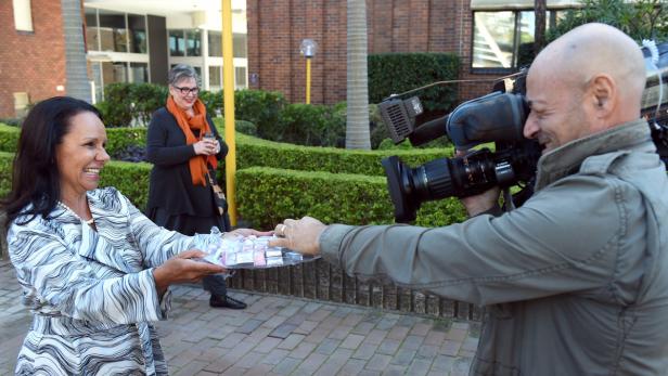 Eine Frau überreicht einem Kameramann eine Platte mit Süßigkeiten.