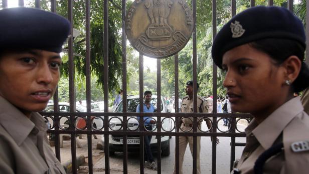 Zwei Polizistinnen stehen vor einem Tor mit dem Emblem des High Court of Delhi.