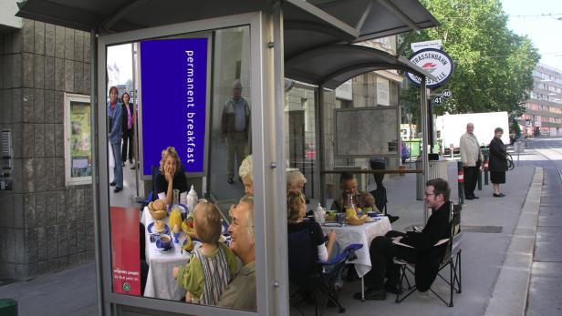 Eine Gruppe von Menschen frühstückt an einer Straßenbahnhaltestelle in Wien.