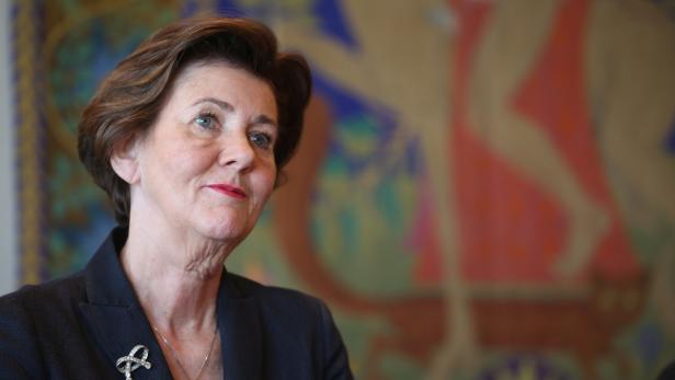 Eine Frau mit kurzem braunem Haar und einem dunklen Blazer blickt nach rechts.