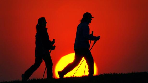 An einem Feld nahe dem südbrandenburgischen Luckau sind am Mittwoch (30.03.2005) bei farbenprächtigem Sonnenuntergang zwei Nordic Walker unterwegs. Durch den Einsatz der Stöcke werden vor allem der passive Bewegungsapparat, die Gelenke, der Rücken, die Knie und die Füße entlastet. Nordic Walking, das flotte Gehen mit Stöcken, findet immer mehr Anhänger. Foto: Patrick Pleul dpa/lbn +++(c) dpa - Bildfunk+++