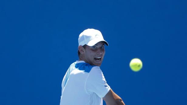Ein Tennisspieler mit weißer Kappe schaut auf einen Tennisball.