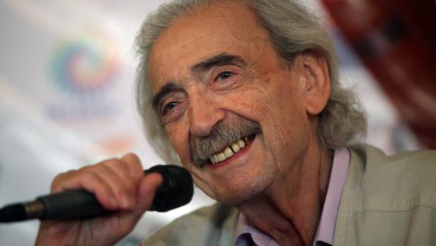 Ein älterer Mann mit grauem Haar und Schnurrbart spricht in ein Mikrofon.