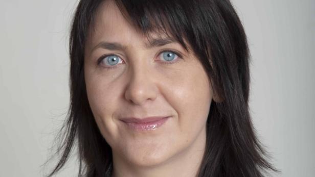 Porträt einer Frau mit dunklen Haaren und blauen Augen.