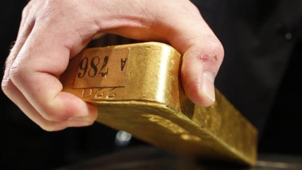 Eine Hand hält einen Goldbarren mit der Aufschrift „982 A“.