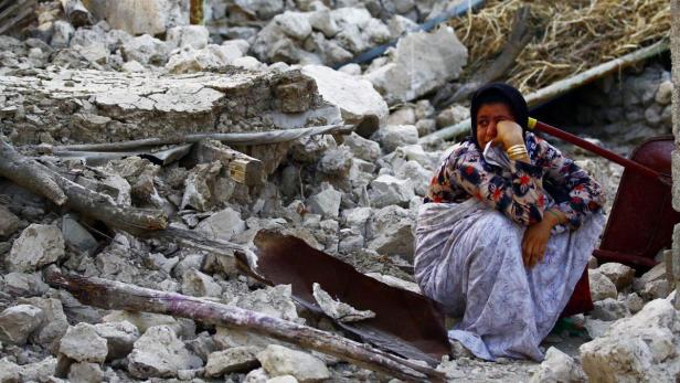 epa03655877 An Iranian woman sits on the rubble in the Shonbeh Twon in Bushehr province in southern Iran, 09 April 2013. The quakes, ranging in magnitude 6.3 on the Richter Scale, shook the Shanbeh town and other communities in Bushehr province in southern Iran on 09 April 2013. At least 37 people were killed in a 6.3-magnitude earthquake near Bushehr in southern Iran, state television reported. EPA/MOHAMAD FATEMI