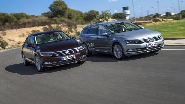Ein burgunderroter und ein grauer VW Passat fahren auf einer Straße.