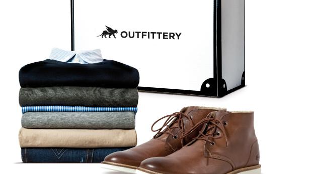 Ein Stapel Kleidung und braune Lederschuhe vor einer Outfittery-Box.