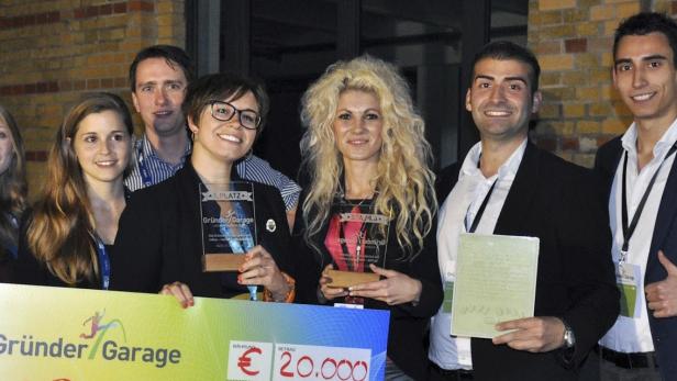 Eine Gruppe von Personen hält einen Scheck über 20.000 Euro und Auszeichnungen der „Gründer/Garage“.