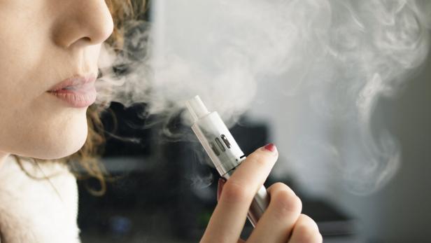 Eine junge frau raucht eine E-Zigarette.