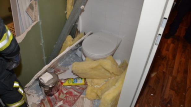 Ein zerstörtes Badezimmer mit einer Toilette und herumliegenden Trümmern.