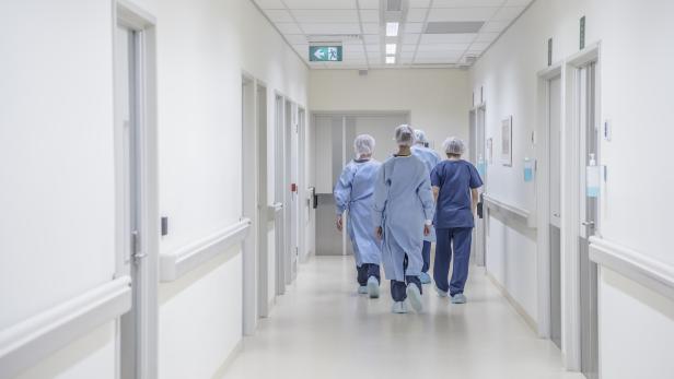 Rear view of surgeons walking down hospital corridor wearing scrubs