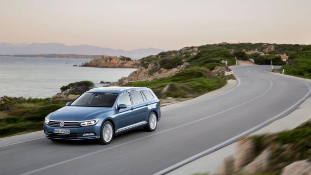 Ein blauer VW Passat fährt auf einer Küstenstraße entlang.