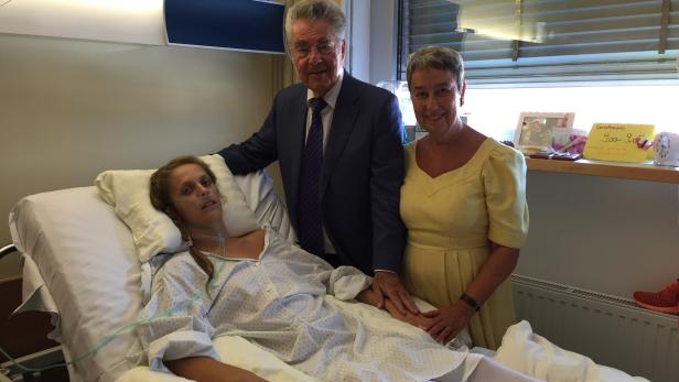 Ein Mann und eine Frau besuchen eine junge Frau im Krankenhaus.