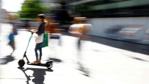 A young woman rides an e-scooter through a pedestrian area in Frankfurt