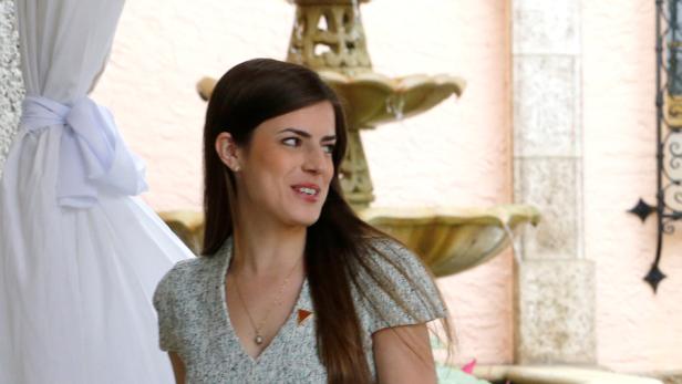 Eine Frau steht vor einem Brunnen und einem drapierten weißen Tuch.