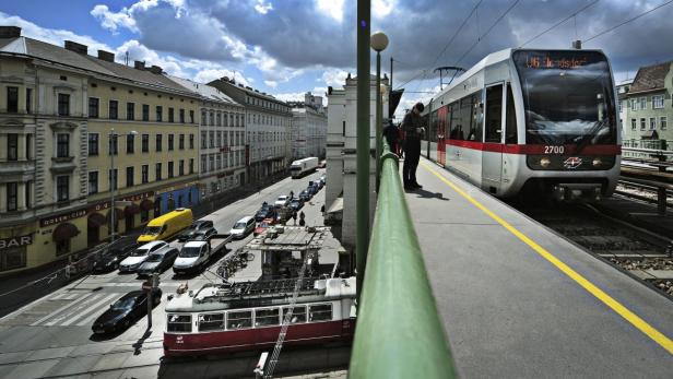 Blick auf eine Wiener Straße mit Autos, einer Straßenbahn und einer U-Bahn-Station.