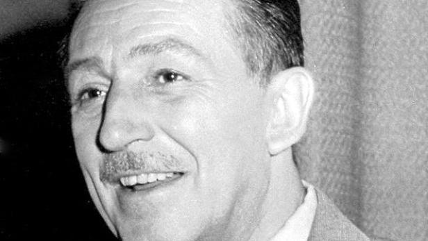 Ein Schwarzweißporträt von Walt Disney, der lächelt.